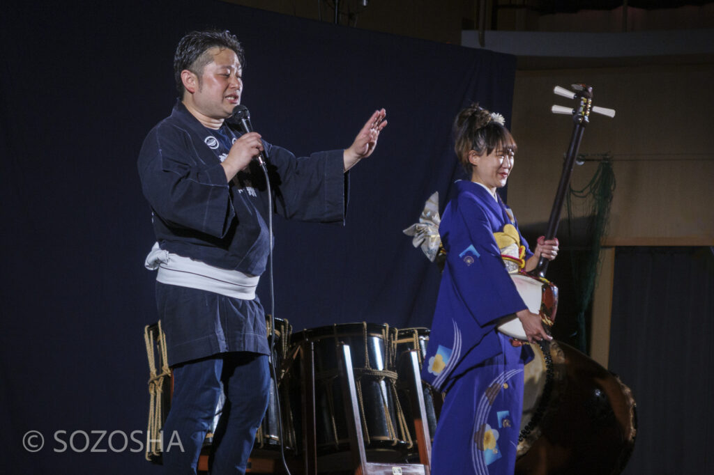 演者が三味線について説明する楽器紹介コーナー | 和楽器の魅力をドラマチックに | 中学校で芸術鑑賞会 | 和楽器・邦楽器・コンサート |和楽器演奏集団独楽 | 和太鼓、箏(琴)、三味線、篠笛、獅子舞|