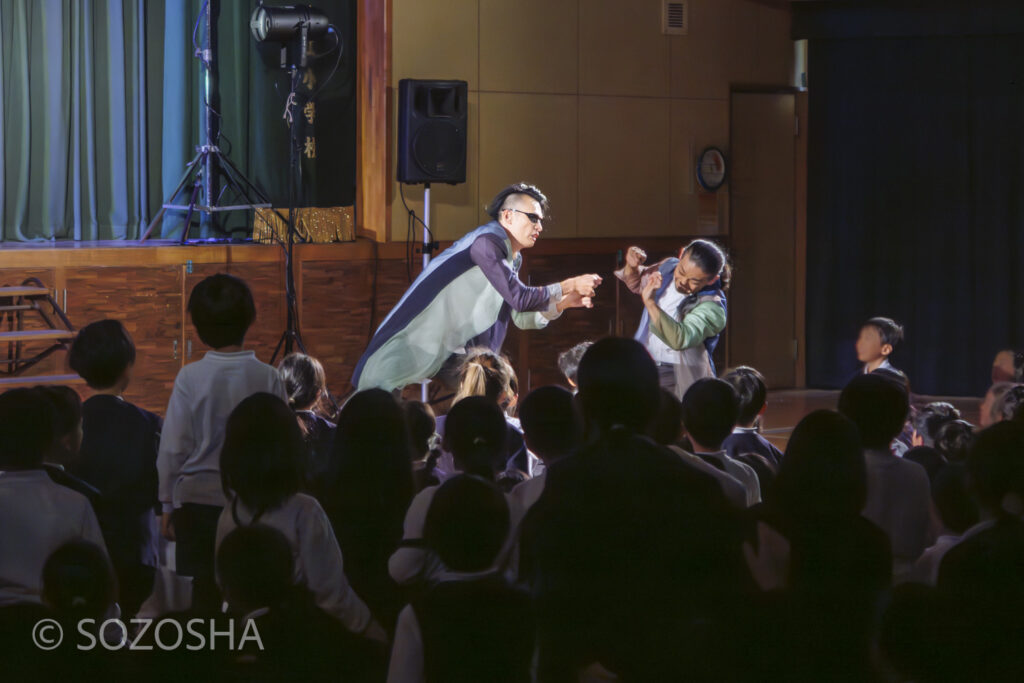 俳優2人が児童の近くまで降りてきて、目の前で掛け合いのマイムを披露している。 | 芸術鑑賞会 | パントマイム |マイムボックス〜おしゃべりなカラダ〜 | いいむろなおき